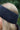 A close up of a blonde lady's head outdoors wearing a slate grey knitted headband.